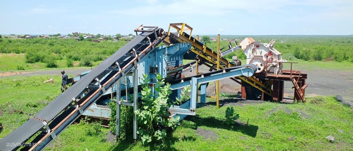 A conveyor-fed screening line operating on open ground at a materials production site.