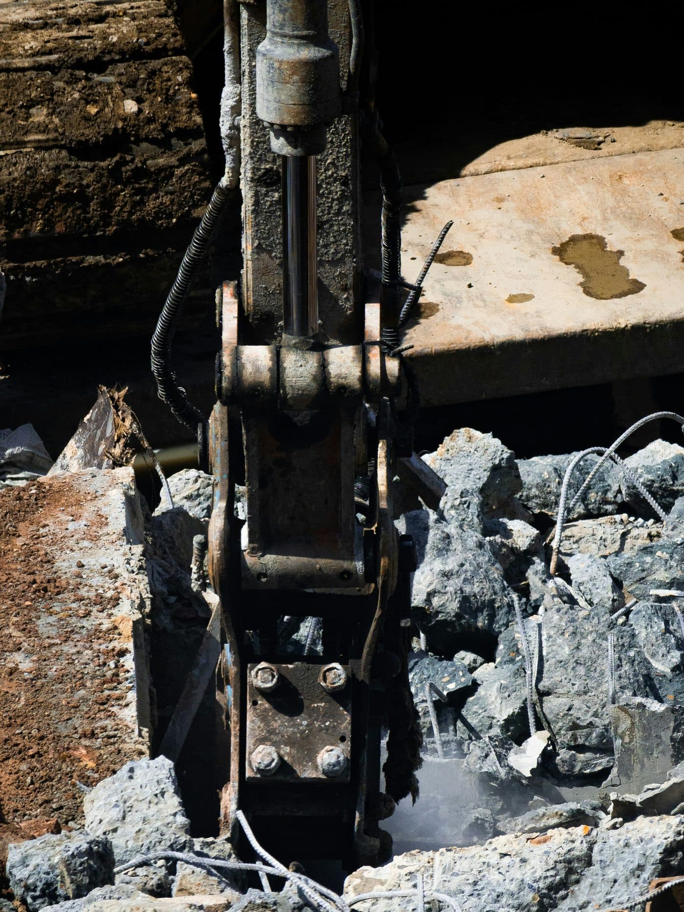 A hydraulic rock breaker working stone inside a confined excavation lit by site lighting.