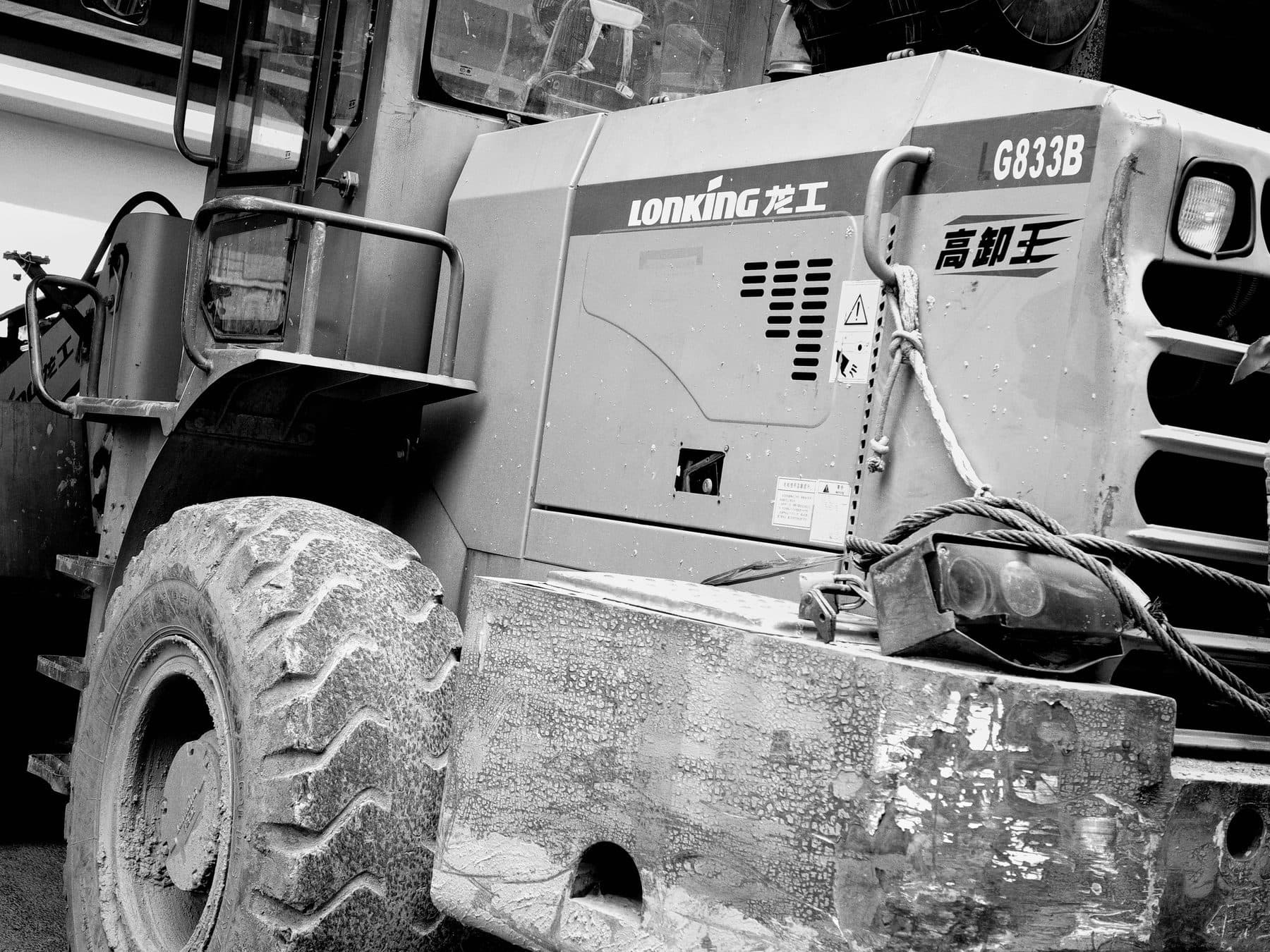 A wheel loader photographed in black and white, its bucket resting on the ground.